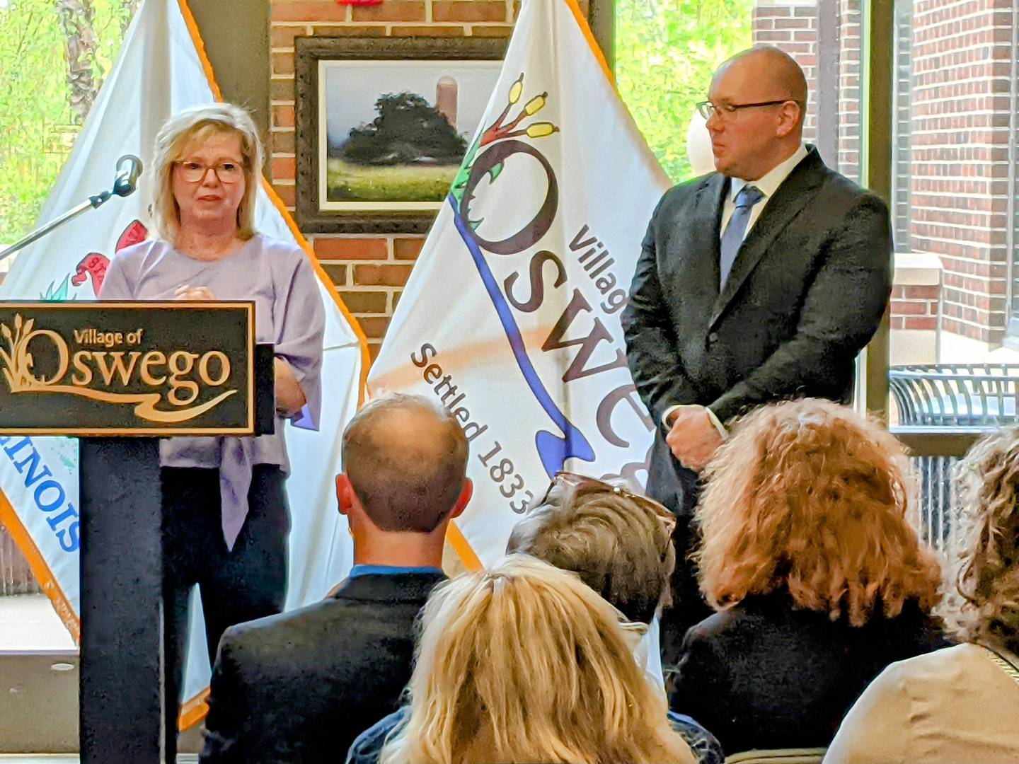 Oswego Village Trustee Karen Novy speaks to those gathered at a reception and swearing-in ceremony prior to the May 6 Village Board meeting, including Village President Ryan Kauffman, right.