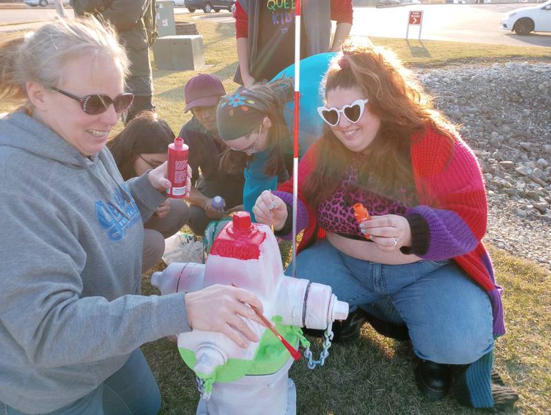 Geneva artist Chrissy Swanson (left) and Batavia resident Annie Hex repaint the Pride-painted fire hydrant Tuesday night after it was vandalized with red paint. The hydrant at the northwest corner of Kirk Road and East State Street, was painted in rainbow and transgender colors last year as part of the city’s Art on Fire Program. It was vandalized several times last summer.