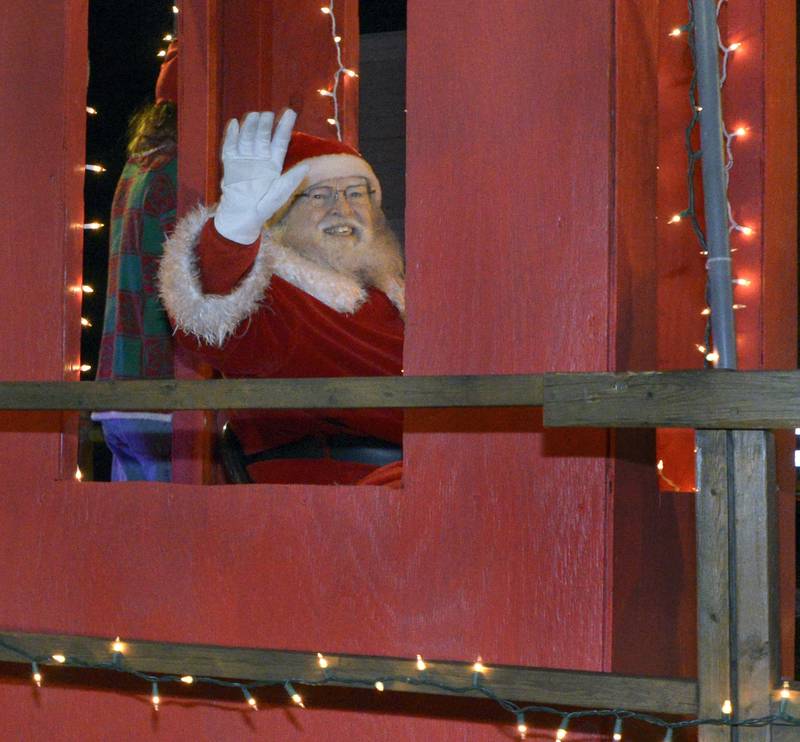 Santa waves to the crowd as he travels along Main St Saturday during the annual Holiday Magic Lighted Santa Parade in Marseilles.