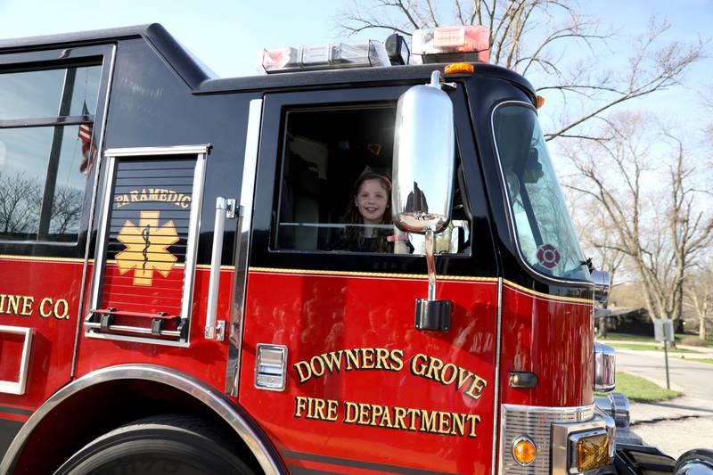 Belle Aire Elementary School third-grader Kyla Richardson waves to her classmates from the front seat of a Downers Grove Fire Department truck on Thursday, April 13, 2023. Kyla won the trip by entering a contest sponsored by the  Fire Department as part of the Learn Not to Burn program.
