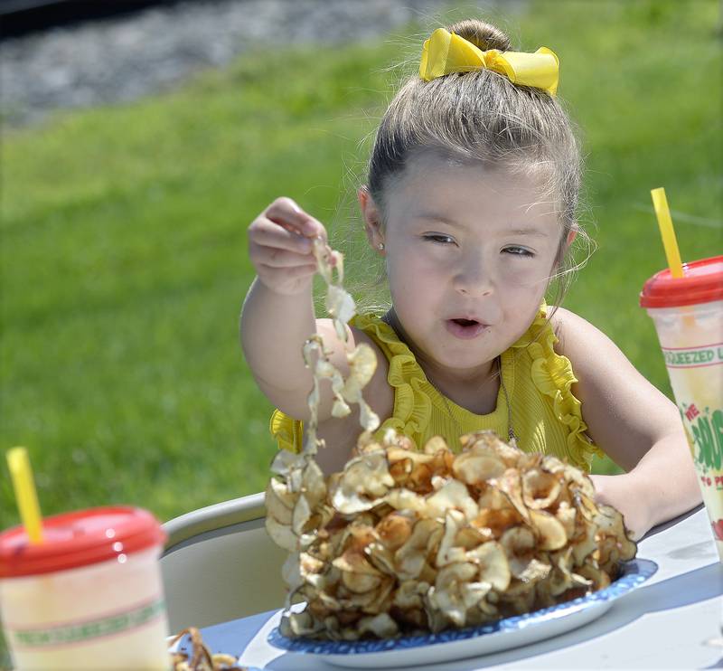 Lennyn Highland tries to figure out how to eat her “twisty chips” Saturday, Aug. 19, 2023, during the annual Grand Ridge Community Fest. The food fair offered a variety of food to sample.