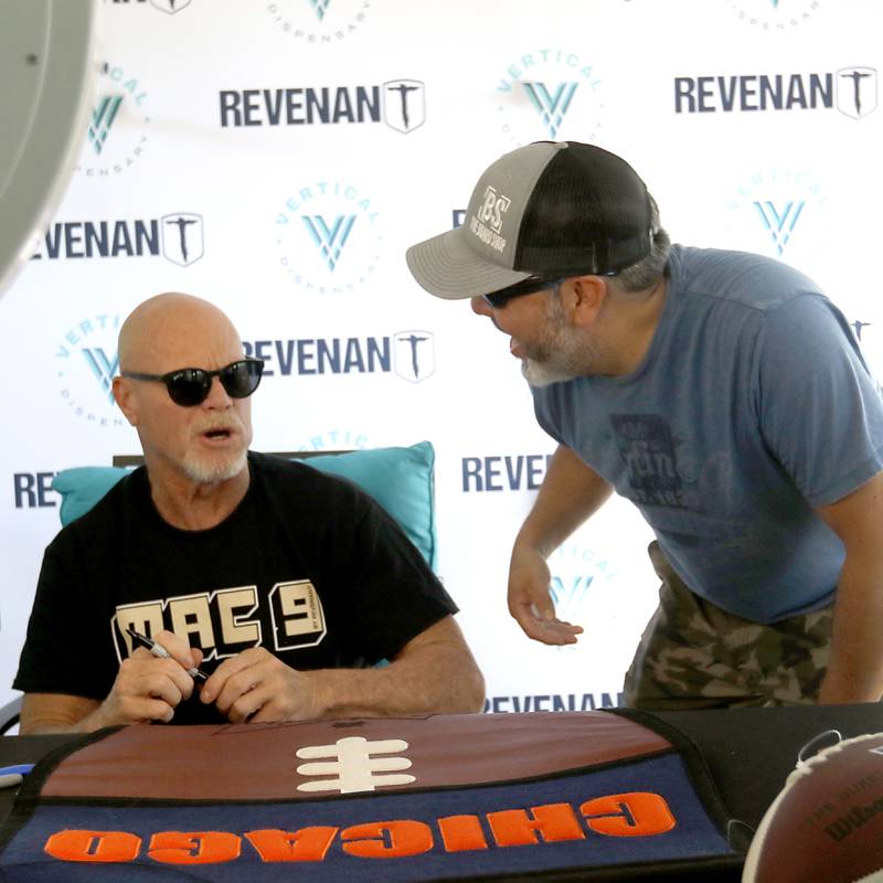 Paul Valdilles of Cary talks with former Bears quarterback Jim McMahon as he signs autograph for him during the grand opening of the Vertical Dispensary on Saturday, Sept. 30, 2023, in Cary. The dispensary has been open for about a month.