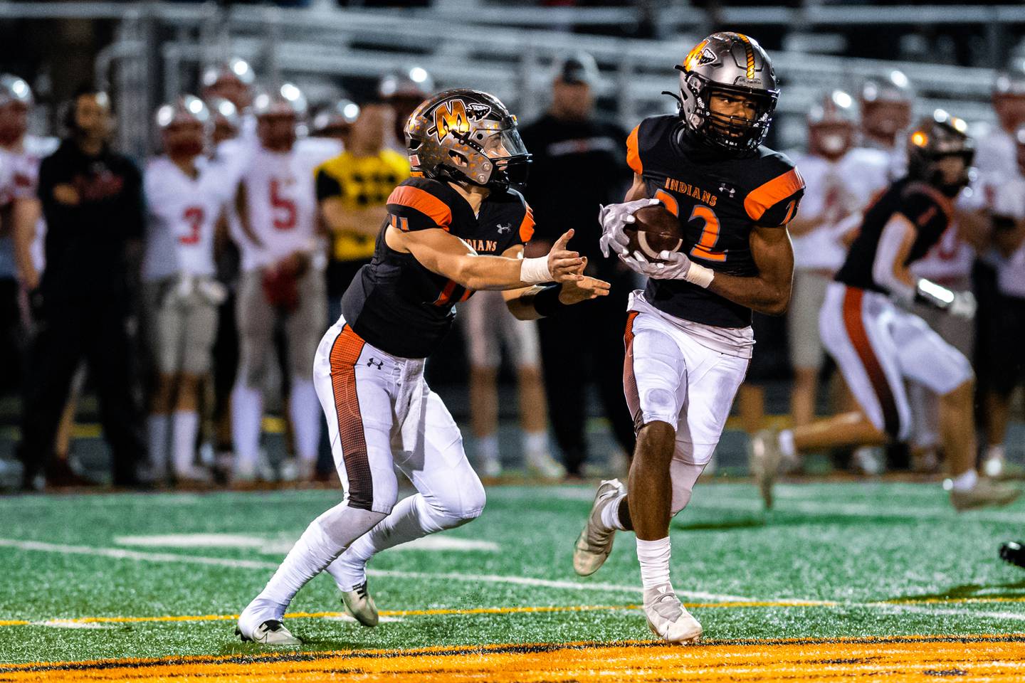 Minookas Gavin Dooley hads the ball off to Joseph Brown during the 2nd round IHSA Class 8A playoff game against Palatine Friday Nov. 4, 2022 at Minooka High School