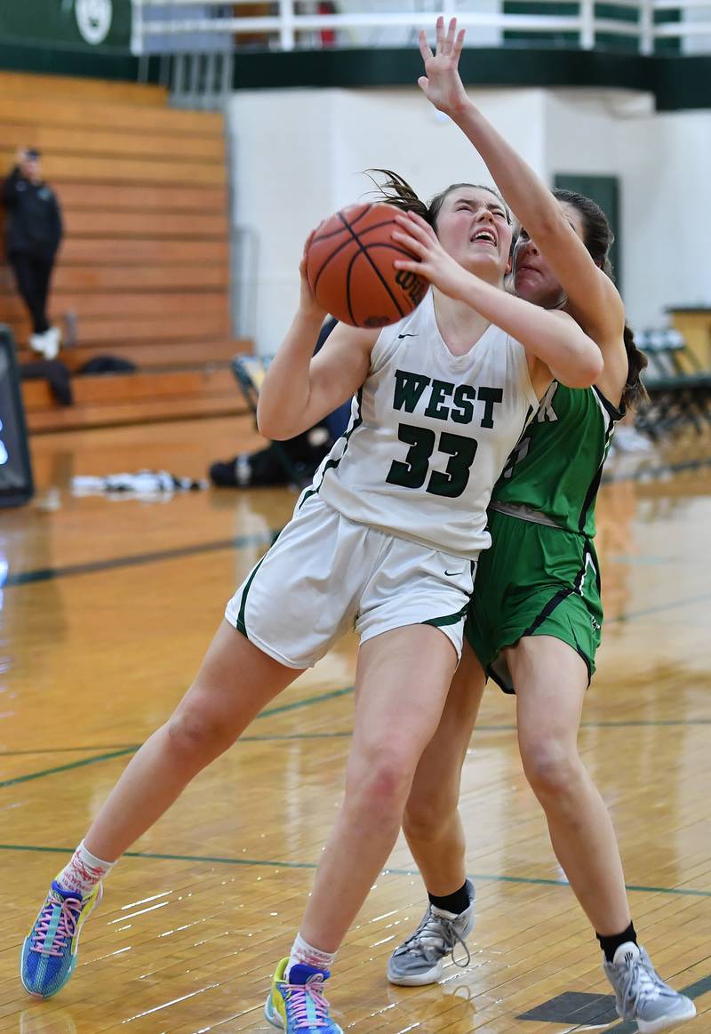 Glenbard West's Makenna Yeager (33) drives to the basket for the winning score as York's Mia Barton defends ending a game on Jan. 22, 2024 at Glenbard West High School in Glen Ellyn.