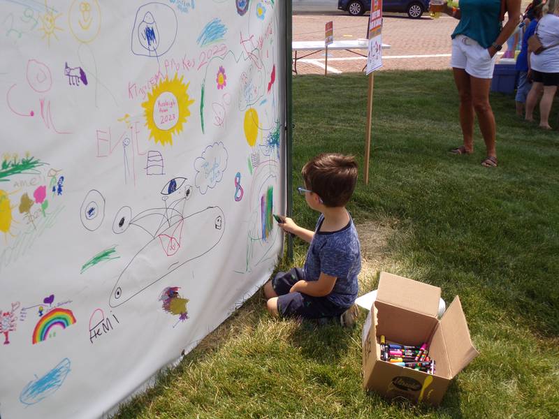 Sam Lanore draws on the kid's poster Saturday, June 3, 2023, during the Shrimp and Brew Hullabaloo at Rotary Park in Princeton.