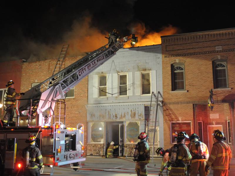 La Salle and Utica firefighters use La Salle's aerial truck to knock down flames above Skoogs Pub & Grill on Sunday, May 10, 2015 downtown Utica.