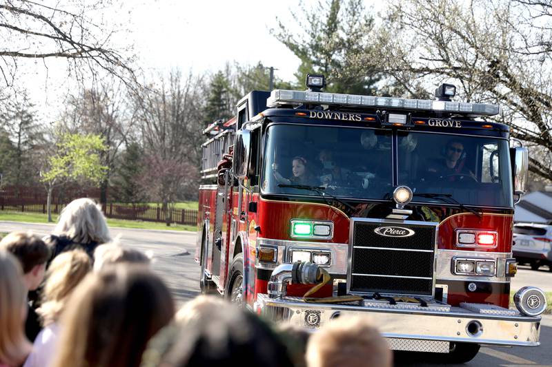 Belle Aire Elementary School third-grader Kyla Richardson waves to her classmates from the front seat of a Downers Grove Fire Department truck on Thursday, April 13, 2023. Kyla won the trip by entering a contest sponsored by the  Fire Department as part of the Learn Not to Burn program.