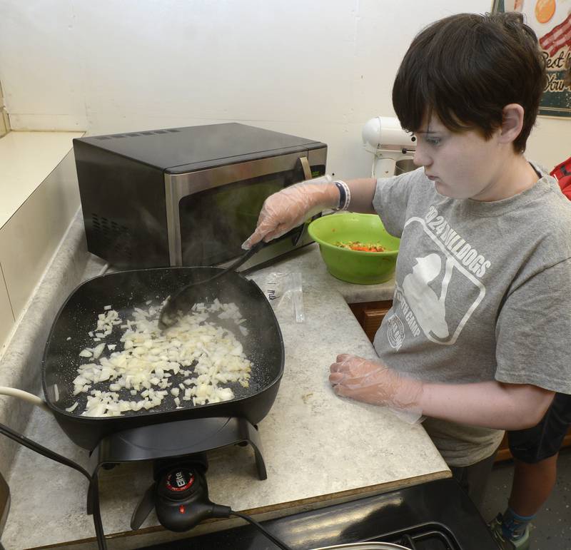 Marshall Volkman begins to stir fry some onions as part of making Veggie Chow Mein Wednesday at Northlawn Junior High in Streator during the Illinois Junior Chefs program.