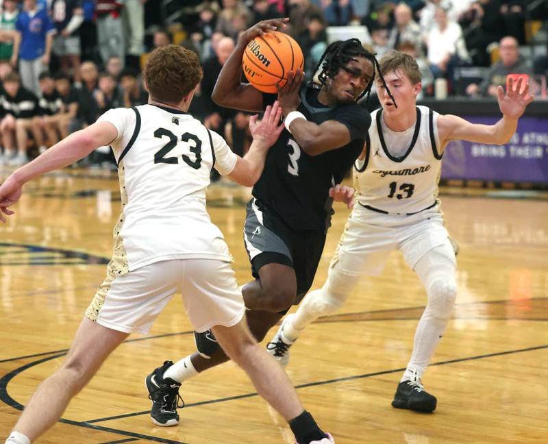 Kaneland's Marshawn Cocroft goes between Sycamore's Aidan Mesenbrink (left) and Xander Lewis during their game Friday, Jan. 9, 2025, at Sycamore High School.