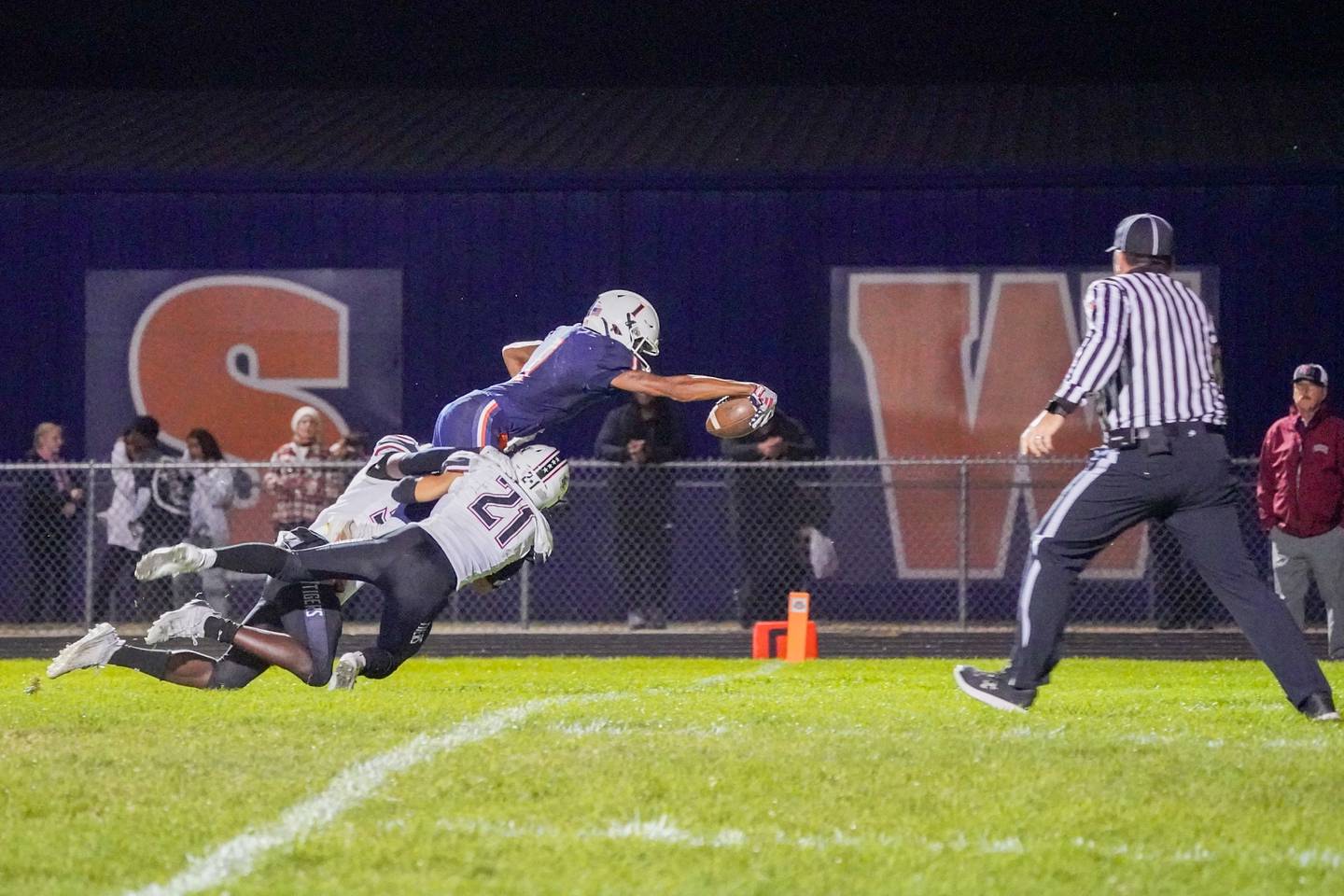 Oswego’s Jeremiah Cain (1) dives into the end zone for a touch down against Plainfield North's Jack Tota (5) and Lucas Frydrychowski (21) during a football game at Oswego High School on Friday, Sept. 27, 2024.