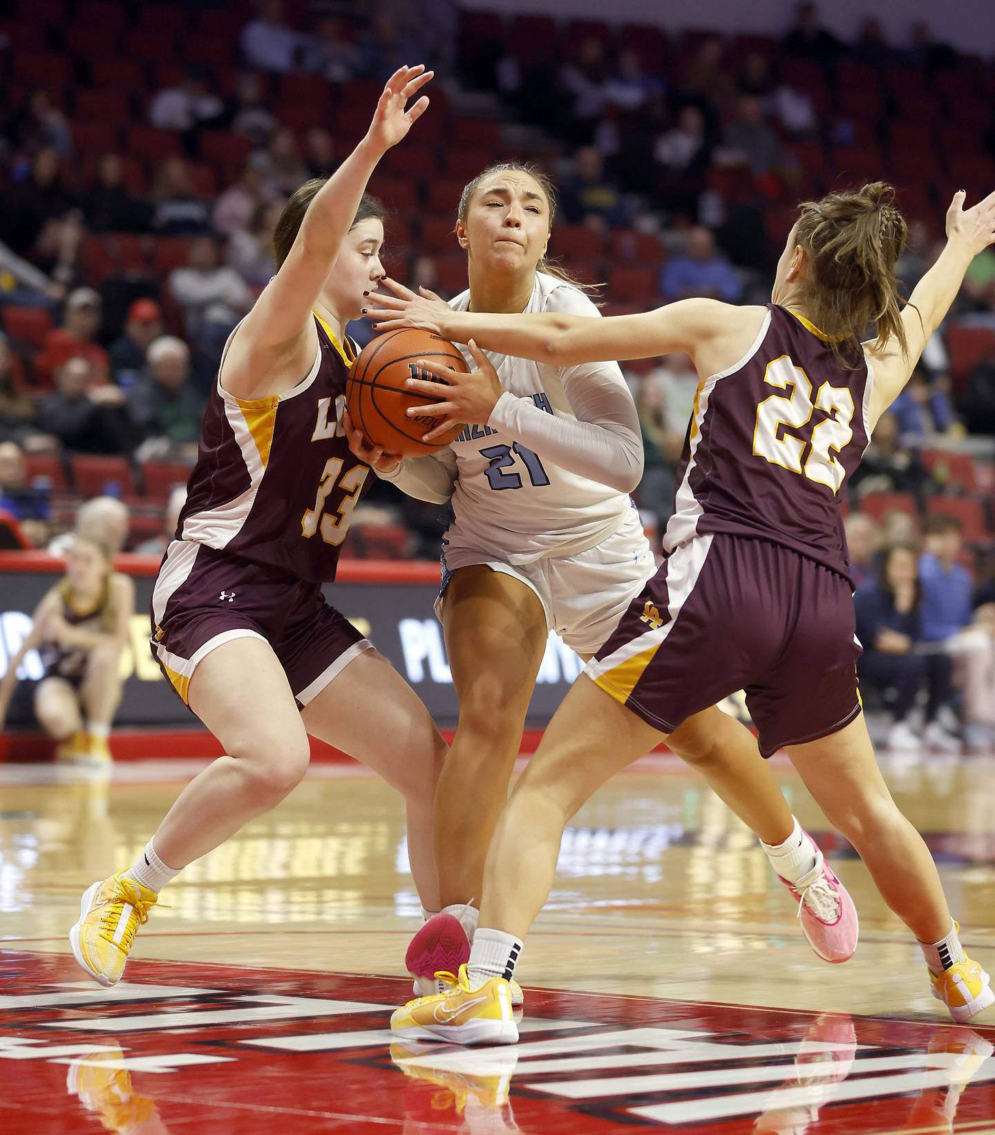 Nazareth Academy's Olivia Austin (21) is sandwiched between Loyola Academy's Paige Engels (33) and Kelsey Langston (22) during the IHSA Class 4A Girls Basketball championship game Saturday, March 2, 2024 at the CEFCU Arena in Normal.