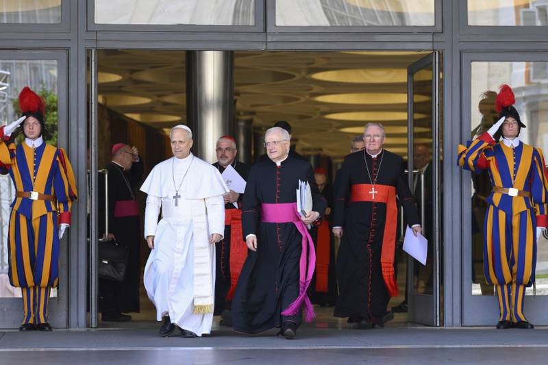 Pope Leo XIV, left, is flanked by Monsignor Leonardo Sapienza, second from left, after his meeting with the College of Cardinals in the New Synod Hall at the Vatican, Saturday, May 10, 2025. (Vatican Media via AP)