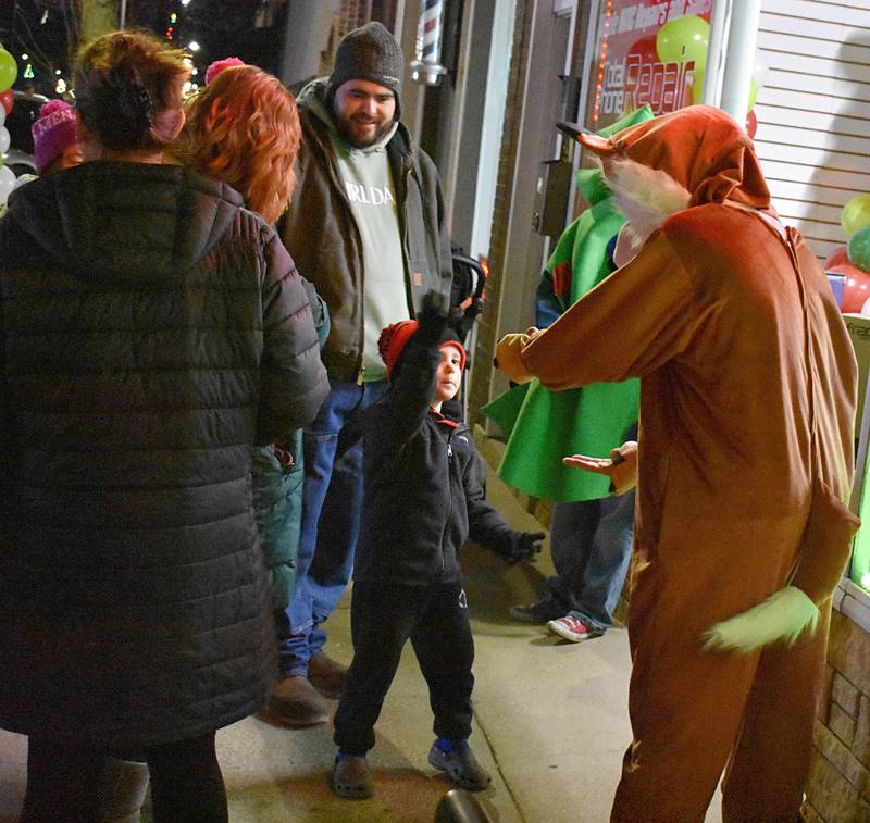 A youngster high-fives one of Santa’s reindeer during Rock Falls’ Hometown Holidays Christmas Walk, Friday, Nov. 21, 2025.