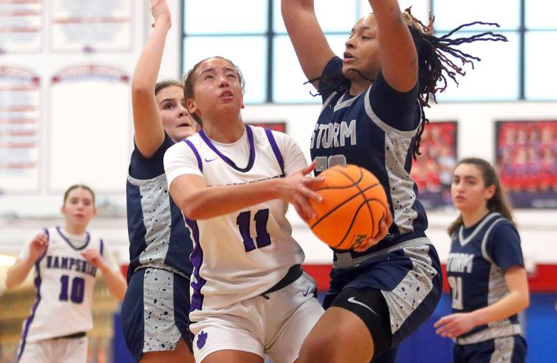 Hampshire’s Mikala Amegasse, center, moves the ball against South Elgin’s Liv Miller, right,  in varsity girls basketball Komaromy Classic tournament  action on Monday, Dec. 29, 2025, at Dundee-Crown High School in Carpentersville.