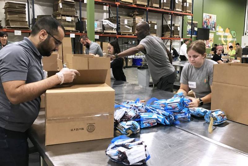 Employee volunteers from Plexus Corporation in Buffalo Grove inspect and package energy bars Wednesday, Aug. 16, 2023, at the Northern Illinois Food Bank's north suburban distribution center in Lake Forest.