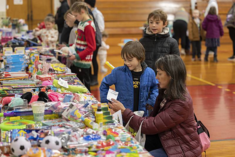 Katie Selberg helps sons George, 6,  and Henry, 9, pick out items as gifts Saturday, Dec. 9, 2023 during Tampico’s Christmas in the Country event. School children earned points by good deeds and family activities and could trade those points in for gifts.
