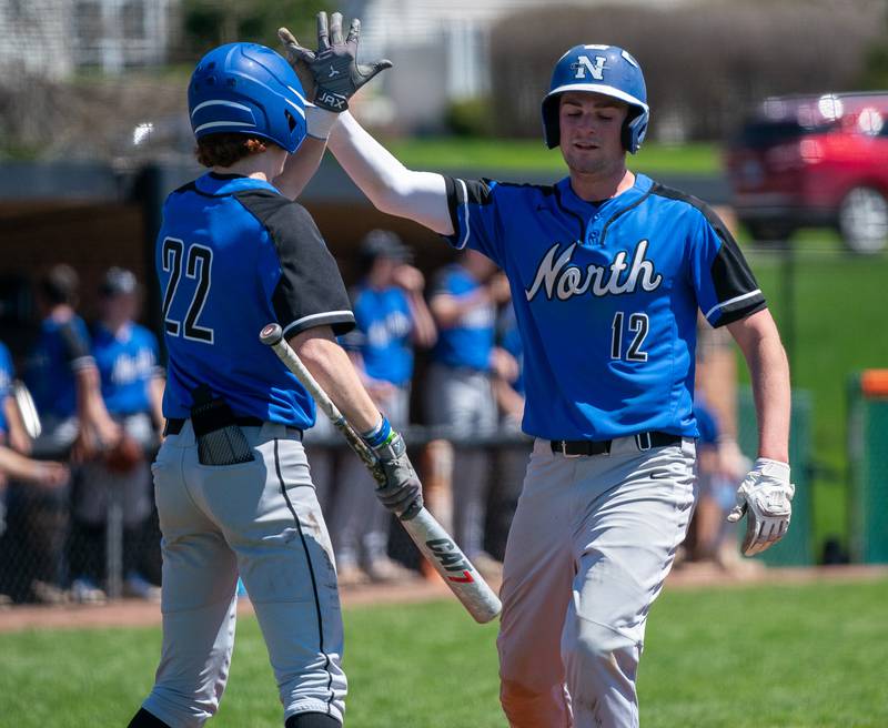 St. Charles North's Aidan Pieper (12) is greeted at home by Jackson Spring (22) after scoring a run against St. Charles East during a baseball game at St. Charles East High School on Saturday, May 7, 2022.