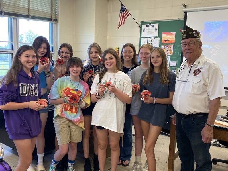 Herrick Middle School students spend time Tuesday, May 23, 2023, with Downers Grove VFW Century Post 503 member Ray Adams, a Vietnam veteran. The students made clay poppies to honor veterans for Memorial Day. Adams brought poppy pins to the students during his visit. (Courtesy Herrick Middle School)