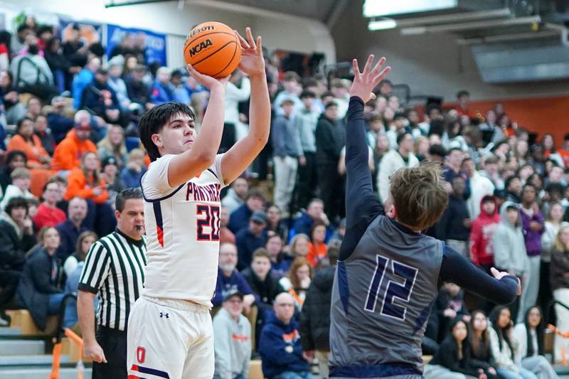 Oswego’s Michael Delgado (20) shoots a 3-pointer against Oswego East's Lukas Adolfs (12) during a basketball game at Oswego High School on Tuesday, February 18, 2025.