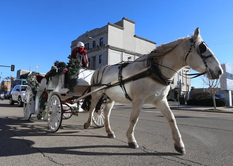 People ride a carriage pulled by a horse on Saturday, Dec. 3, 2022 as part of the Miracle on First Street event downtown La Salle.