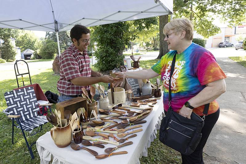 Julie Hoak of Polo buys a handmade wooden spoon from Michael Krabbenhoeft Saturday, July 6, 2024 during the Nuts About Art exhibit at John Dixon Park.