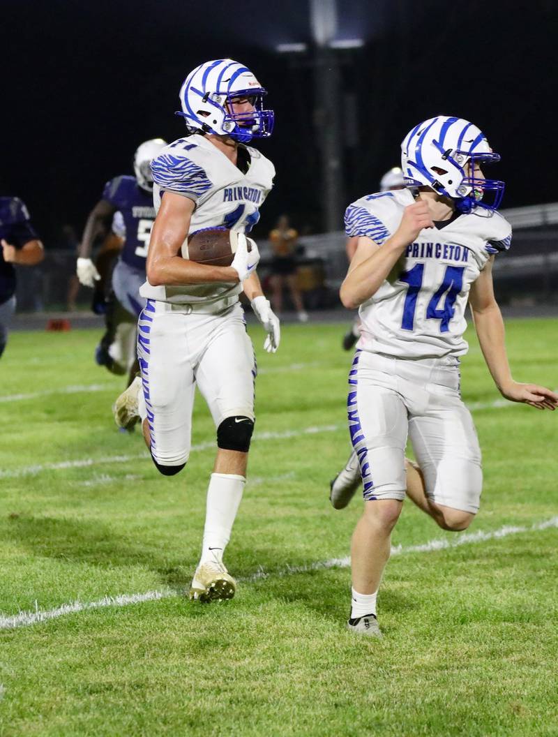 Princeton quarterback Will Lott (14) leads Noah LaPorte down the sidelines at Monmouth-Roseville Friday night. Princeton won 40-0.