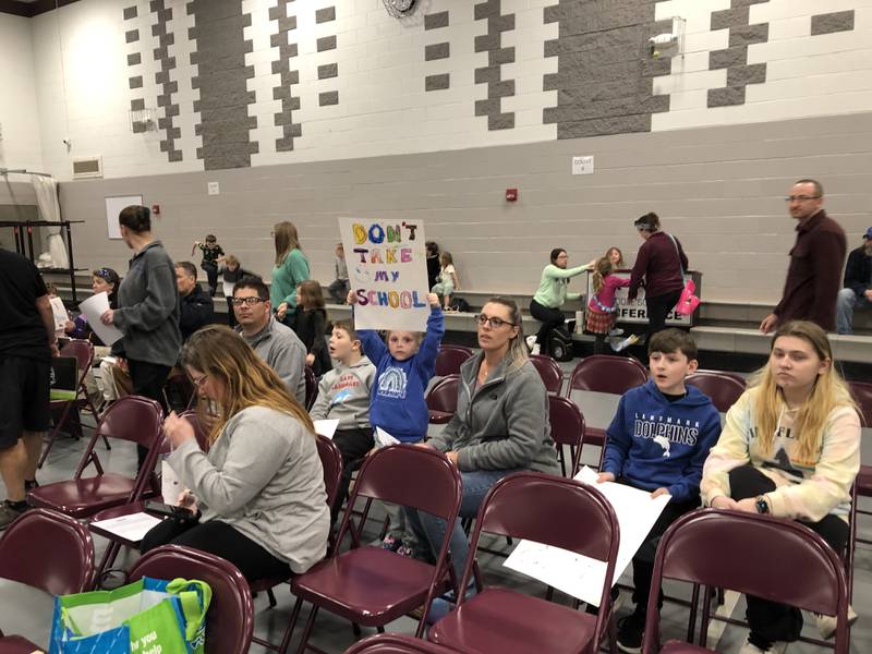 A child holds up the poster she made showing support of Landmark School on Monday, April 22, 2024. A public hearing was held at McHenry Middle School as District 15's board of education considers closing the 130-year-old building at the end of the 2024-2025 school year.