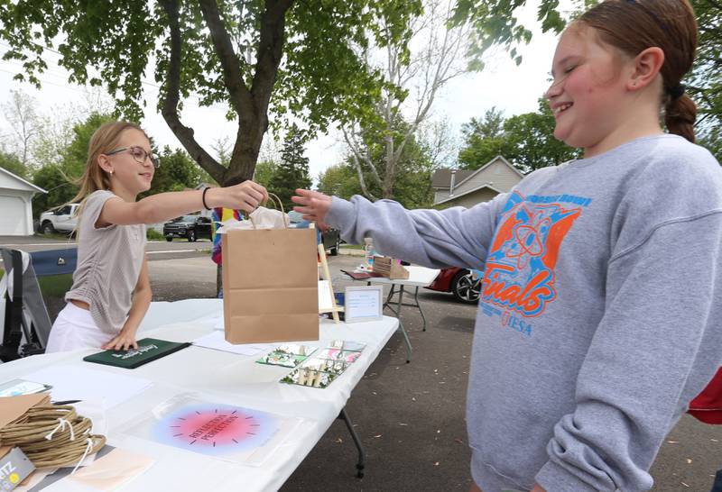 Emma Radtke of Utica hands Kourtney Brauhn of Ottawa a mirror that she made to sell at the the 2nd Annual Lemonade Day for Young Entrepreneurs on Saturday, May 4, 2024 at Country Kids in Utica.