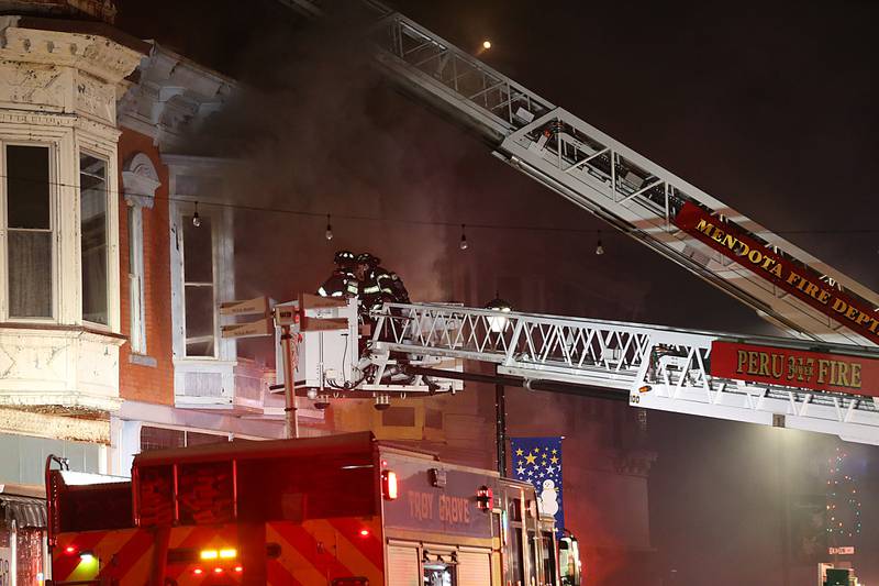 Peru firefighters use their aerial ladder trucks  to spray down flames at 708 Illinois Avenue on Friday, Dec. 30, 2022 downtown Mendota.