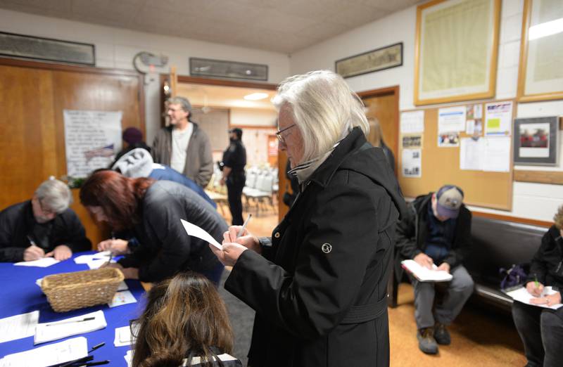 Downers Grove residents including Claudia Feeney write down their questions and share their appreciation for US Rep Sean Casten after the Downers Grove town hall meeting Wednesday March 19, 2025. The meeting ended as a result of too many people being asked to save the question/answers for a later time and Casten being interrupted with questions regarding the unrest between Israel and Palestine.