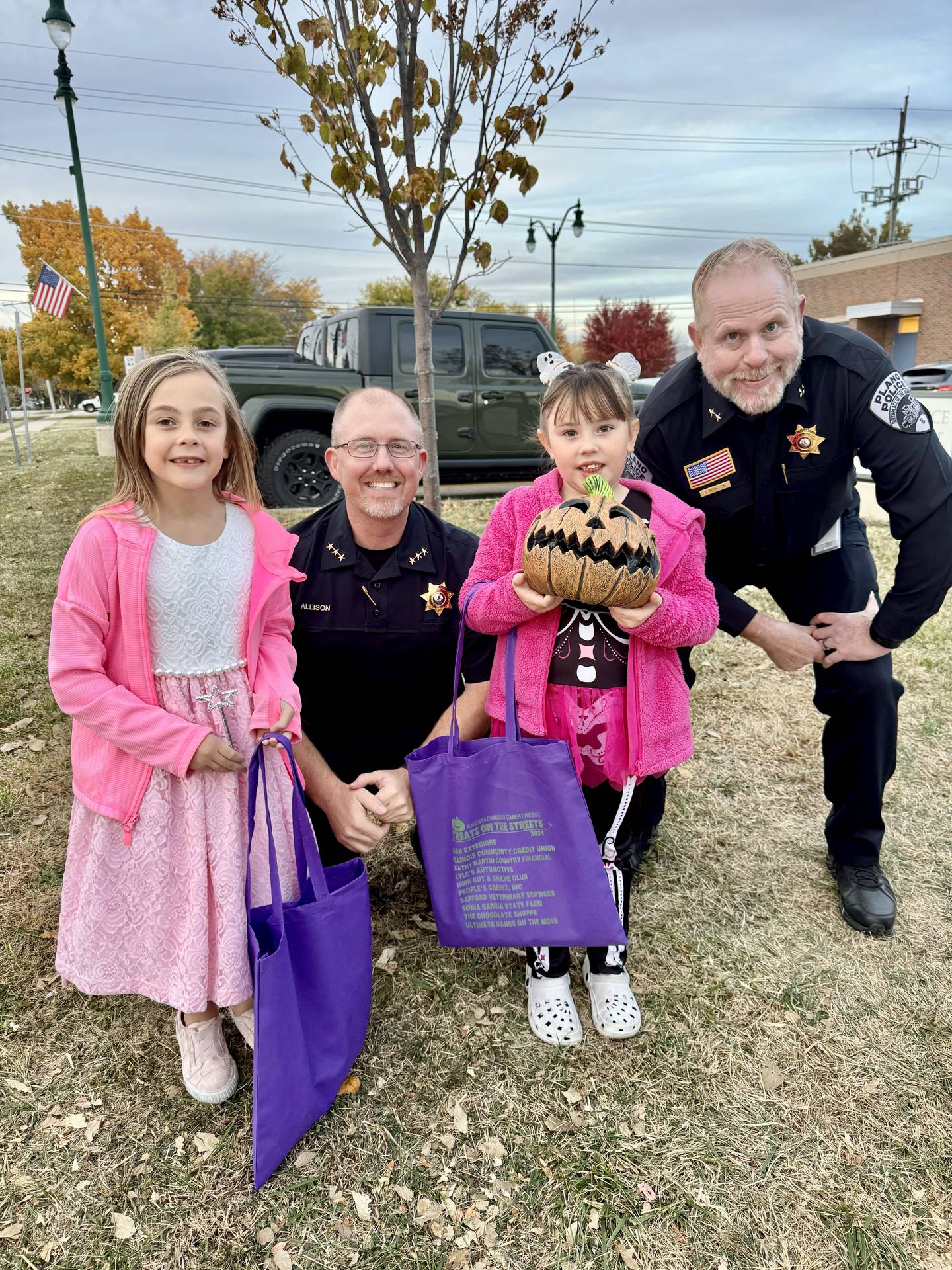 Tiffany Forristall's daughters, dressed as a fairy and pink-tutu skeleton, pose with some of Plano's members in blue at the town's "Treats in the Streets" Halloween event.