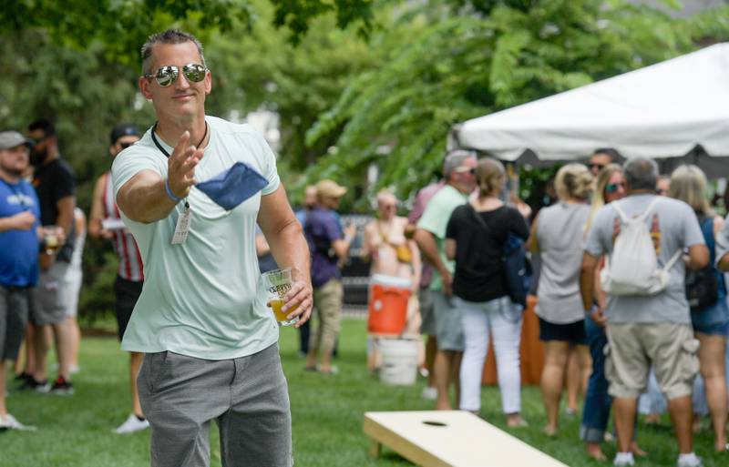 Dave Piszczek plays bags while enjoying one of the many a craft brews at Wheaton Brew and Seltzer Fest in Memorial Park on Saturday, August 6, 2022.