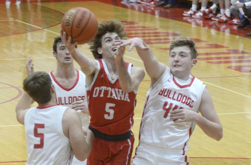 Ottawa's Aiden Mucci (5) gets a shot past Streator defender Nolan Lukach (44) as Adam Williamson (5) and Christian Benning trail the play Saturday, Dec. 10, 2022, at Pops Dale Gymnasium in Streator.