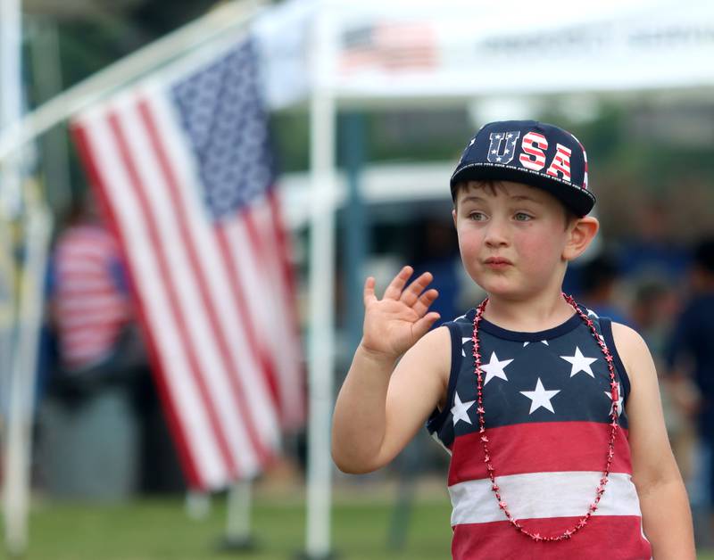 Cullen McDevitt, 3, of Harvard, waves Saturday, July 2, 2022, during the Red, White and Blue Food Truck FEASTival at Milky Way Park in Harvard.