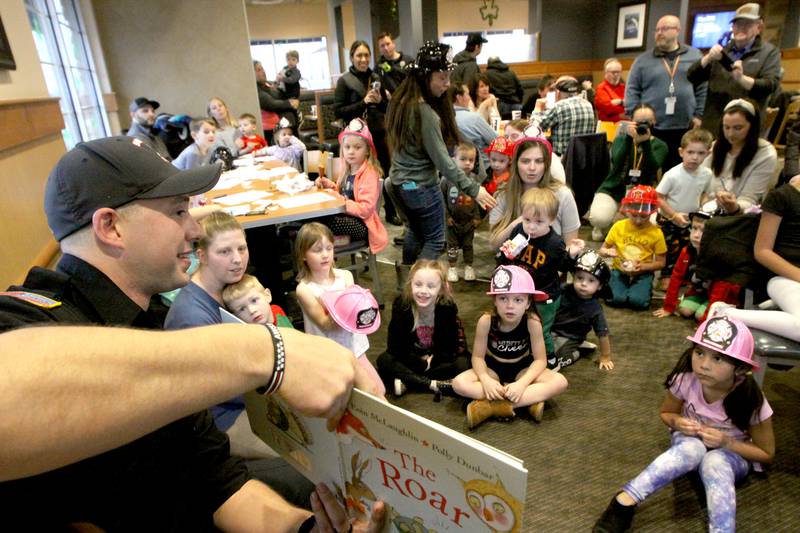Youngsters listen as Huntley firefighter Brad DeRaedt reads a storybook during a Read & Eat Fries With a Firefighter event Thursday, March 16, 2023, at the Culver’s in Huntley.