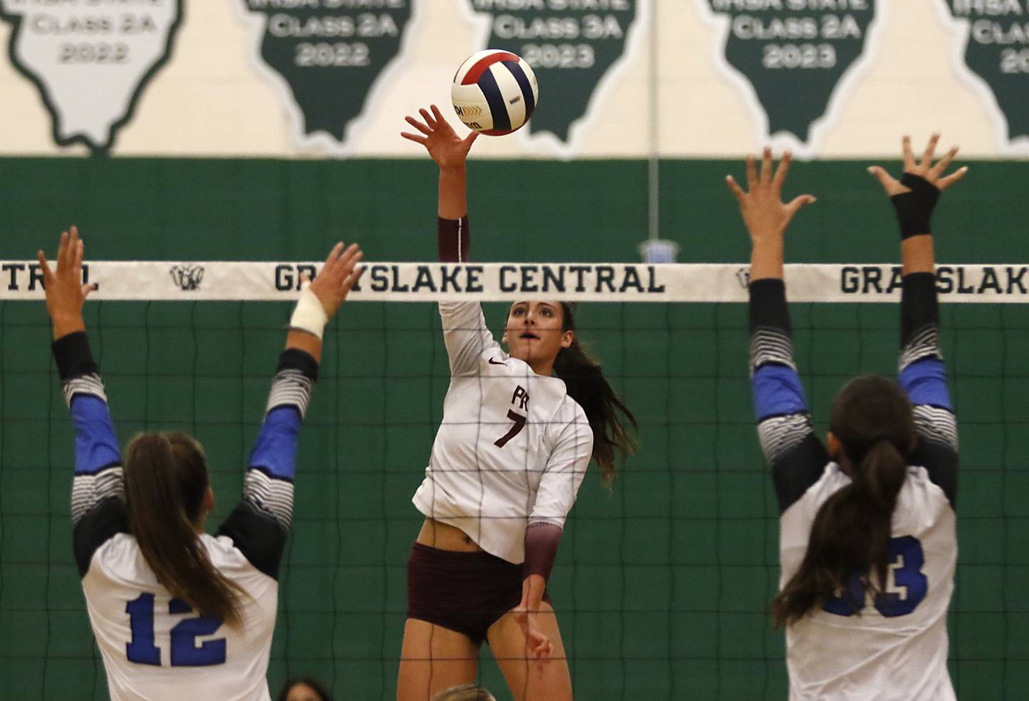 Prairie Ridge's Maizy Agnello (center) hits the ball between St. Francis' Jenna Glaudel (left)  and Emma Delaney (right) during the IHSA Class 3A Grayslake Central Supersectional volleyball match on Monday, Nov. 11, 2024, at Grayslake Central High School.