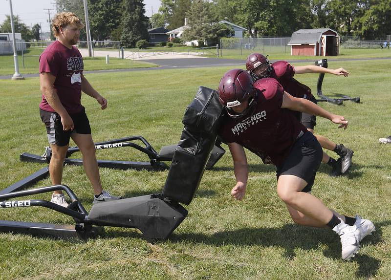 Marengo’s Ryan Grismer (center) and Brady Kentgen (right) run a blocking drill during football practice on Tuesday, July 22,  2025, at Marengo High School.