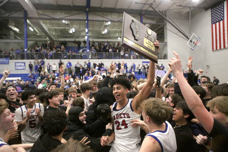 Marmion Academy’s Trevon Roots hoists the hardware after a win in IHSA Class 3A Sectional title game action at Burlington Central High School Friday night.