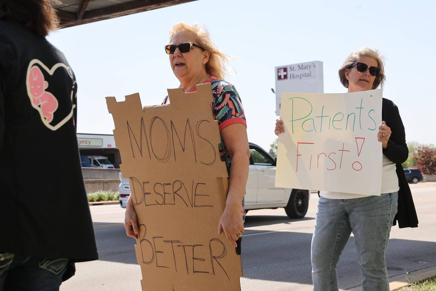 Dr. Valerie Goldfain, left, a longstanding doctor with Westwood Obstetrics & Gynecology, joins a group rallying in protest of Prime Healthcare ending its contract with Westwood's practice at Saint Mary's Hospital along West Court Street in Kankakee on Saturday, May 10, 2025. Dr. Goldfain stands with local mothers and Westwood patients, including Laurie DeYoung, right, of Bourbonnais.