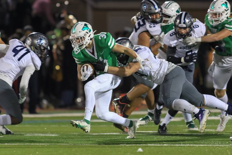 York's Jake Melion (30) drags Oswego East's Jack Benson (54) for extra yards during Class 8A Playoff football game between Oswego East at York.  Oct 28, 2022.