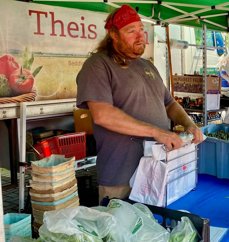 Rob Pondelick, fifth generation farmer at Theis Farm Market and Greenhouse based in Maple Park, speaks to a customer at the opening day of the DeKalb farmers market on Thursday, June 5, 2025, in Van Buer Plaza in downtown DeKalb. The market opened its 30th year Thursday.