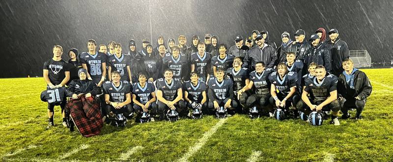 Former and current Bureau Valley players gather around longtime Storm assistant coach Craig Johnson, who is retiring from the sidelines this year.