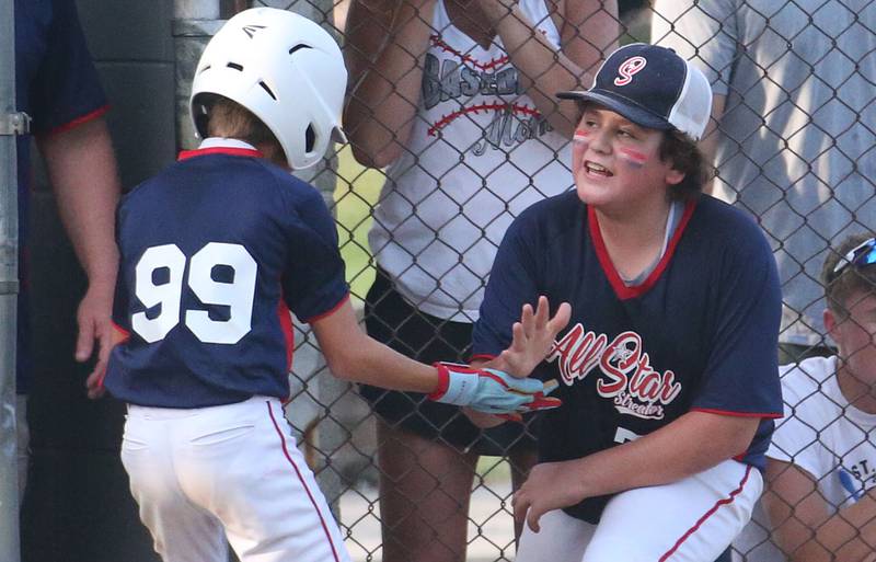 Streator All Stars players Bradley Matsko hi-fives teammate Noah Rodriguez after scoring a run against Ottawa American during the District 20 championship game on Sunday, July 14, 2024 at Washington Park in Peru.