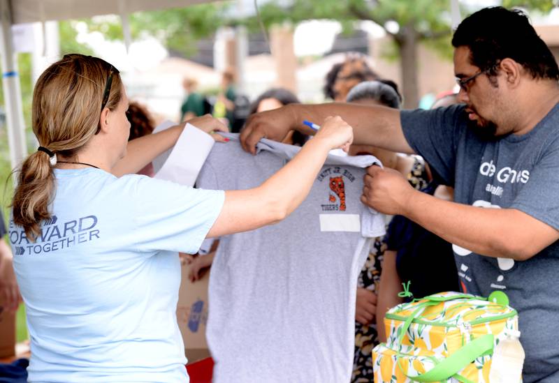 Goodwin Principal, Dana Tiede and Ruby Flores of Cicero help choose the right size gym uniform shirt for Ruby's daughter (not shown)  during the Back to School Fair held at the Cicero Community Park Sunday Aug 13, 2023.