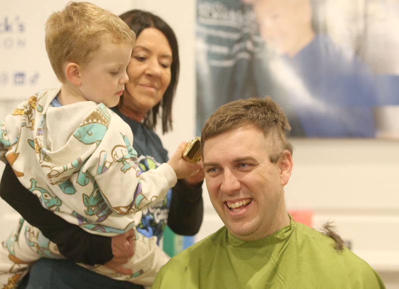 Evan Brown, held by Jennifer Stoneking, takes the "first swipe" of hair from his father Ben Brown, during the 18th annual Illinois Valley Emergency Services St. Baldrick's event on Sunday, March 23, 2025 at Senicas Oak Ridge in La Salle. Ben Brown was the organizer of the St. Baldrick's event that started in 2007. Since then, the event has raised over $250,000 and shaved over 1000 heads.