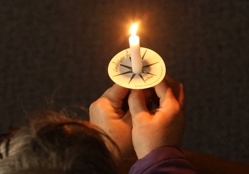 A parishionesr holds a candle during Holy Thursday Mass on Thursday, March 2, 2026 at St. Mary's Catholic Church in Utica.