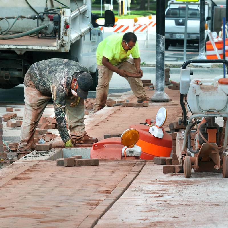 Workers lay bricks on the sidewalk Wednesday, Aug. 28, 2024, as construction continues on Main Street in Genoa.
