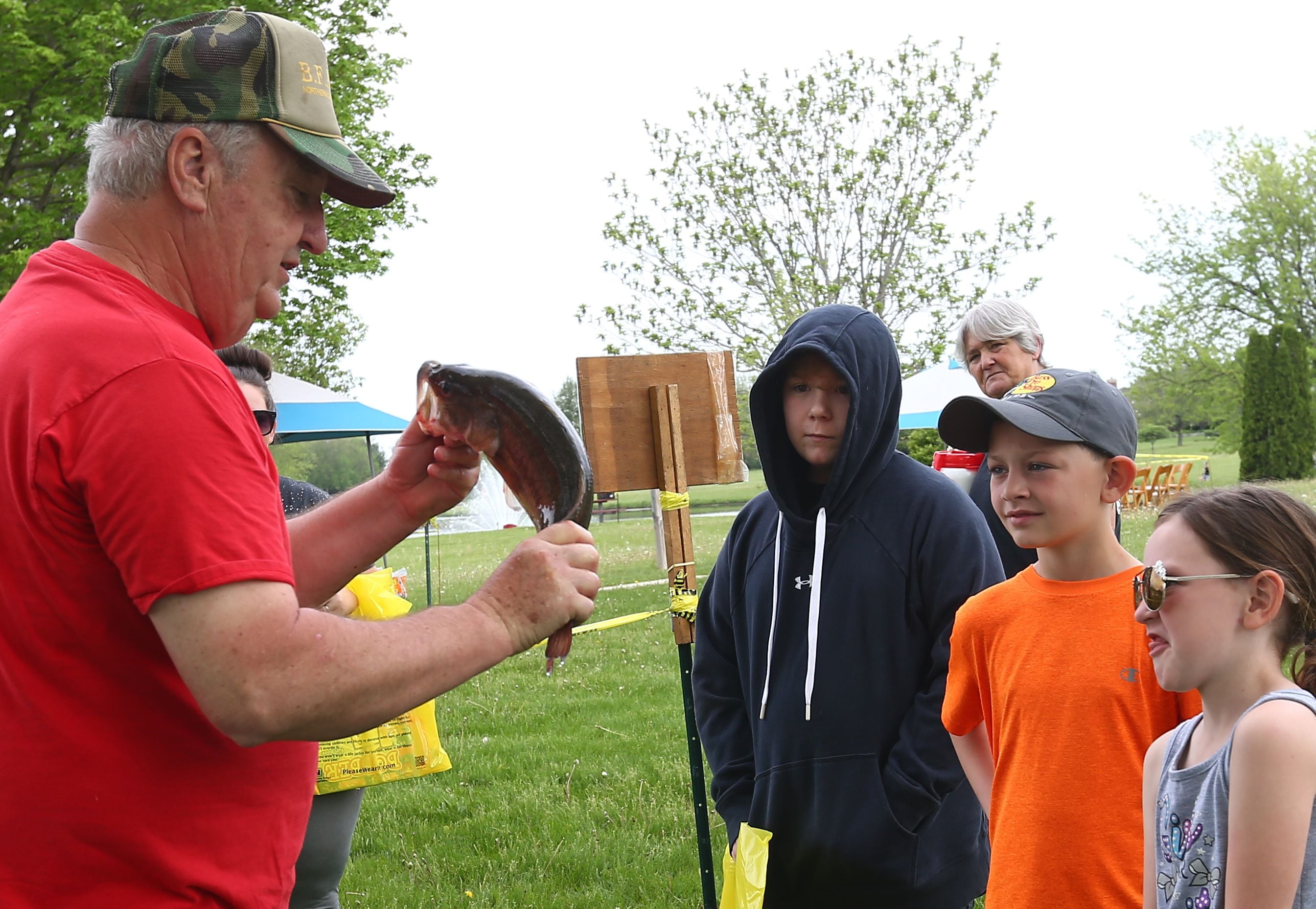 Oh, yuck! Maci Manning, of Dalzell (right), grimaces as Ken Clodfelter, retired fish biologist with the Illinois Department of Natural Resources, teaches her and (from right) brother Jexton and Damien Bezely about several kinds of fish during the 22nd annual Kids Fishing Expo on Saturday, May 14, 2022, at Baker Lake in Peru.