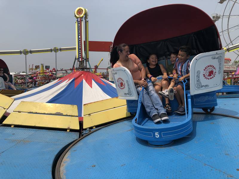 Margarita Gonzalez, left, joins Mya De La Cruz, Mateo De La Cruz, and Oscar Gonzalez on the Tilt-a-Whirl on Sunday, June 4, 2023, during Harvard's Milk Days.