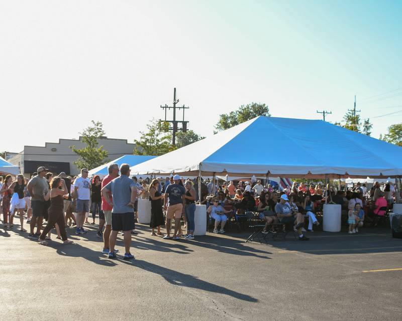 Community members gather around the main tent in front of the stage on Sunday Sep. 1, 2024, during the Cue for a Cause event held in downtown Elmhurst.